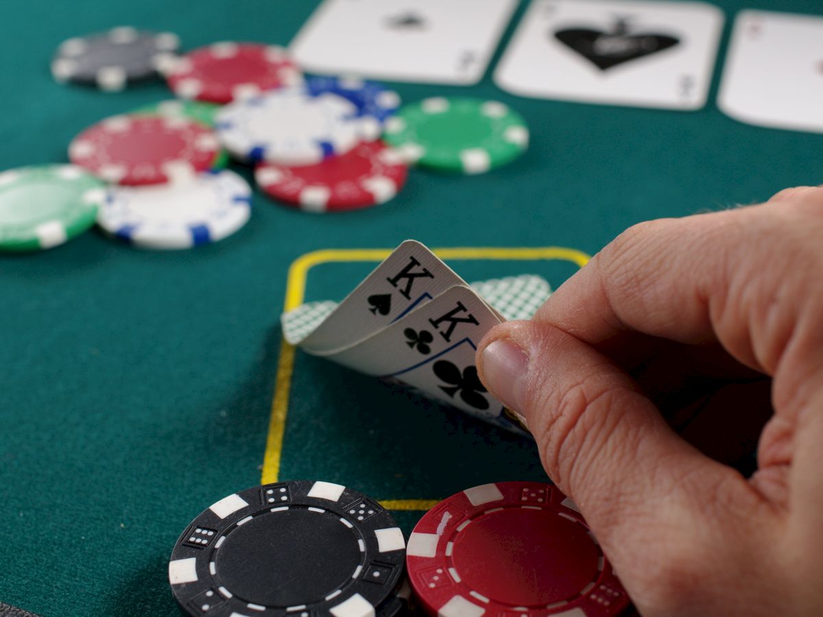 A hand reveals two kings in a poker game with chips and cards scattered on the table.