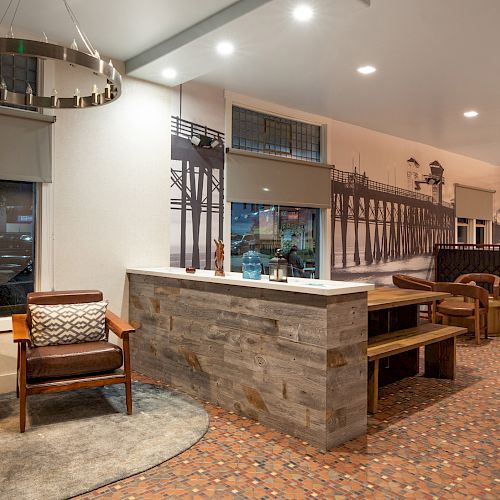 The image shows a modern, cozy lobby area with seating, a large wall mural, and contemporary decor elements, including a pendant light and a wall-mounted TV.