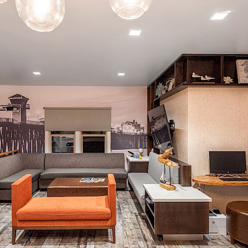 A modern living room with a sectional sofa, orange chair, desk with computer, wall art, shelves, and indoor plants in a well-lit space.